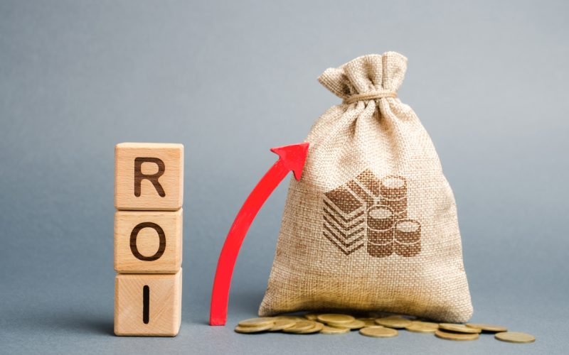 Wooden blocks with the word ROI and the up arrow with the money bag